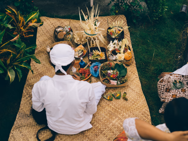 Ceremonia balinesa tradicional con ofrendas canang sari, flores y rituales ancestrales en templo de Bali